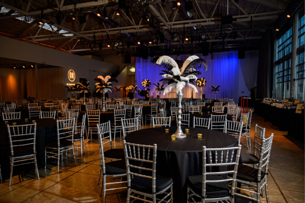 Table settings with black tablecloth and large feather centerpiece