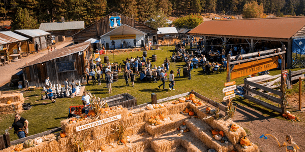 a group of people outside with hay bales and pumpkins